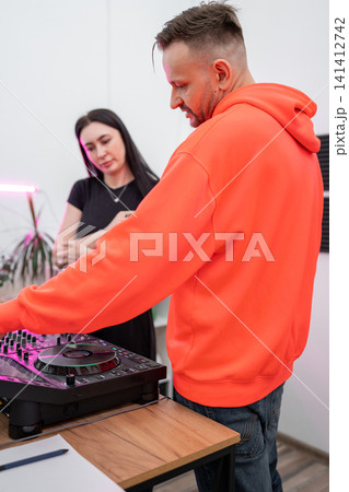 Woman learning DJ skills with mixing console working independently at recording studio desk. DJ, woman, mixing console, learning, studio Woman learning DJ skills with mixing console working independently at recording studio desk. DJ, woman, mixing console, learning, studio 141412742