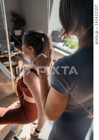 Foot work and core exercise on a Pilates Reformer machine illuminated by sunlight. Fit, healthy and strong authentical body. Fitness concept. 141413107