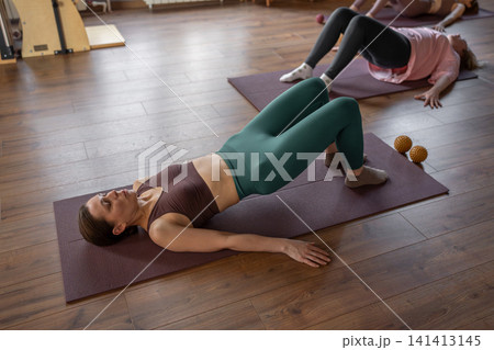 Glute bridge in Pilates workout. Active lifestyle and wellness concept. Stretch on mat in comfy clothes for flexibility and muscle health Glute bridge in Pilates workout. Active lifestyle and wellness concept. Stretch on mat in comfy clothes for flexibility and muscle health 141413145