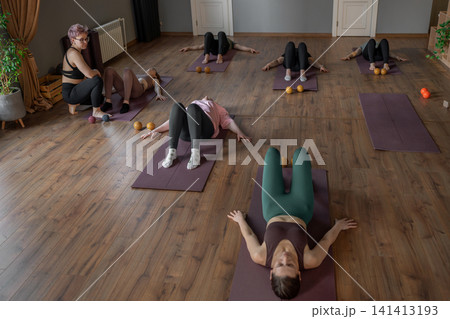 Woman instructor teaching mobility to a group of seniors in a pilates studio. Group of senior people exercising on mats to improve balance and flexibility. Healthy lifestyle and wellness 141413193