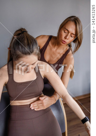 Young caucasian woman doing roll down exercise in a pilates bright studio. Their workout focuses on core strength and flexibility in a modern fitness environment. 141413265