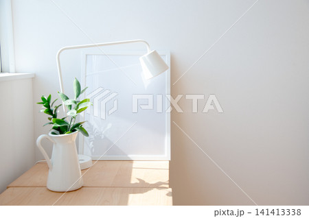デスクライトと白い花瓶の観葉植物を飾った明るい机 141413338