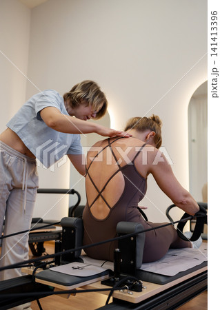 Woman doing rotation exercise on Pilates Reformer for the chest and back muscles, focusing on flexibility, strength, and control with determination 141413396