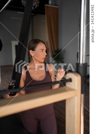 Elegant pilates pair performing synchronized deep stretches using reformer beds in bright wood-floored studio. Synchronized, deep stretch, reformer, studio, wood floor Elegant pilates pair performing synchronized deep stretches using reformer beds in bright wood-floored studio. Synchronized, deep stretch, reformer, studio, wood floor 141413492