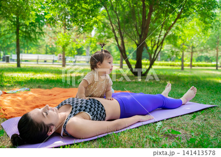 Women relaxing and talking on mats after yoga on green grass under trees in city park. Relaxing, after yoga, mats, talking, grass, city park. Women relaxing and talking on mats after yoga on green grass under trees in city park. Relaxing, after yoga, mats, talking, grass, city park. 141413578