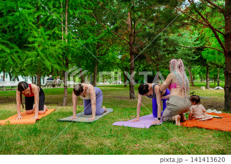 Women in purple activewear doing tabletop yoga pose side by side with child on mats outdoors. Tabletop pose, yoga, mother, child, mats, purple, outdoors. Women in purple activewear doing tabletop yoga pose side by side with child on mats outdoors. Tabletop pose, yoga, mother, child, mats, purple, outdoors. 141413620