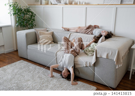 Friends standing upside down on hands and relaxing in cozy living room with plants and soft window light. Relaxing, sitting, friends, cozy, living room, plants. Friends standing upside down on hands and relaxing in cozy living room with plants and soft window light. Relaxing, sitting, friends, cozy, living room, plants. 141413815