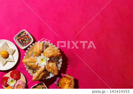 Diwali background with traditional Indian sweets and diya on pink copy space 141414355