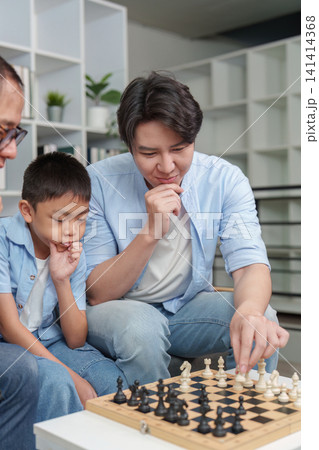 Asian father and son playing chess at home for cognitive development Asian father and son playing chess at home for cognitive development 141414368
