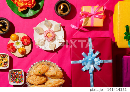 Diwali festive flat lay with traditional Indian sweets gifts and diyas on pink background 141414381