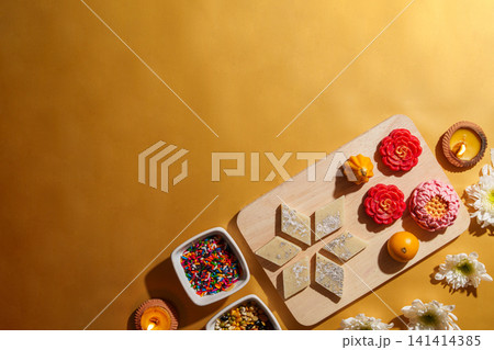 Diwali festival flat lay with traditional Indian sweets and clay diyas on yellow background Diwali festival flat lay with traditional Indian sweets and clay diyas on yellow background 141414385