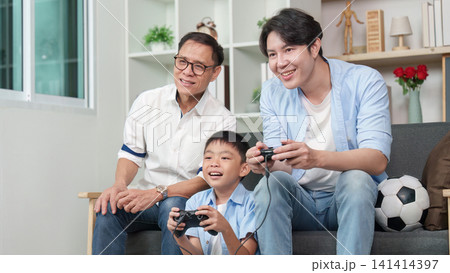 Multigenerational Asian family playing video games in living room Multigenerational Asian family playing video games in living room 141414397