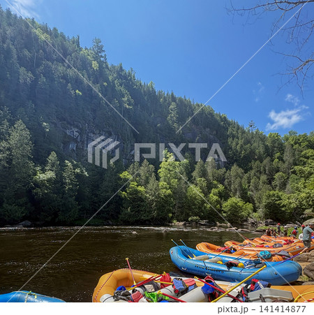 Kayaks Lined up Along the River Under Bright Blue Sky Kayaks Lined up Along the River Under Bright Blue Sky 141414877