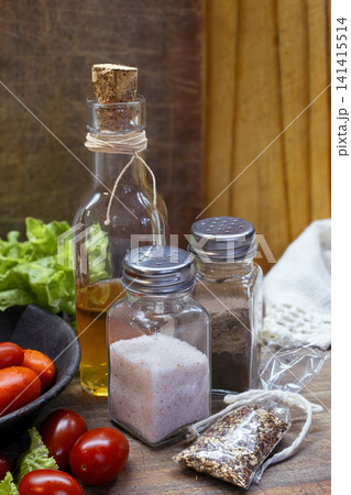 Olive oil, pink salt, pepper, cherry tomatoes, and salad condiments preparing fresh healthy organic meals, seasoning gourmet food with natural ingredients 141415514