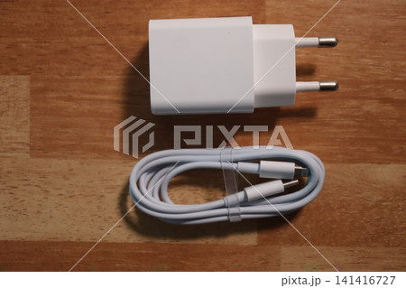 White Power Adapter and Cable on Wooden Surface 141416727