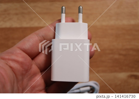 Hand Holding White Power Adapter Charger 141416730