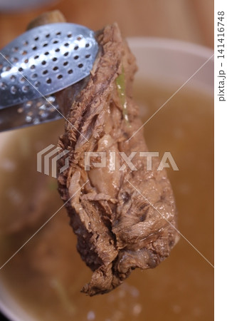 Tender Meat in Broth with Tongs Close-up 141416748