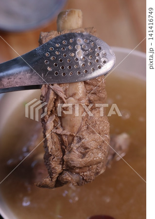 Tongs Holding Tender Pork Rib Over Broth Tongs Holding Tender Pork Rib Over Broth 141416749