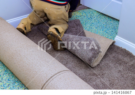 Worker is rolling out old carpet in room is ready for home renovation Worker is rolling out old carpet in room is ready for home renovation 141416867