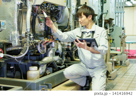 タブレットを持って機械の点検する若い日本人男性作業員　撮影協力：学校法人電波学園　東京電子専門学校 141416942