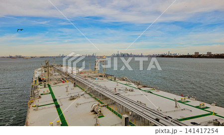 High angle view from oil tanker vessel deck moving in bay with urban city skyline on horizon background during sunny day for maritime transport industry 141417254