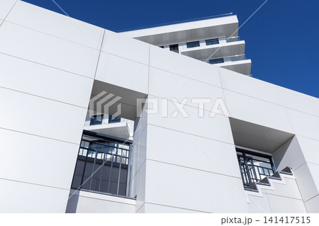 A modern white minimalist building facade under clean blue sky A modern white minimalist building facade under clean blue sky 141417515
