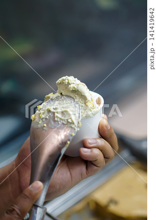 Premium Artisan Gelato Being Scooped into White Paper Cup by Hand Premium Artisan Gelato Being Scooped into White Paper Cup by Hand 141419642
