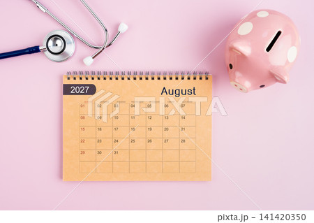 August 2027 desk calendar and stethoscope with piggy bank. Savings for Health concept. August 2027 desk calendar and stethoscope with piggy bank. Savings for Health concept. 141420350