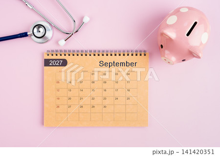 September 2027 desk calendar and stethoscope with piggy bank. Savings for Health concept. September 2027 desk calendar and stethoscope with piggy bank. Savings for Health concept. 141420351