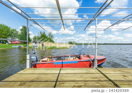 Red Motorboat Moored at Wooden Pier under Metal Canopy 141420389
