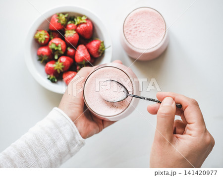 Hands stirring strawberry yogurt with a spoon Hands stirring strawberry yogurt with a spoon 141420977
