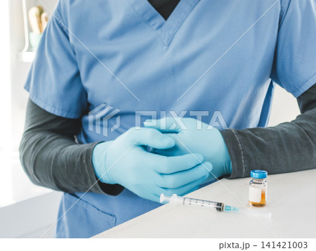 Healthcare worker in a blue scrubs and medical gloves 141421003