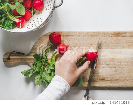 Hands slicing fresh red radishes 141421018