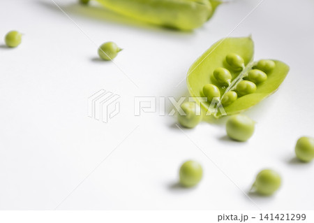 Fresh green peas in open pods isolated on white background. Close up view of organic legumes, healthy food ingredient, raw vegetables, natural harvest, vegan nutrition, vegetarian eating concept. Fresh green peas in open pods isolated on white background. Close up view of organic legumes, healthy food ingredient, raw vegetables, natural harvest, vegan nutrition, vegetarian eating concept. 141421299