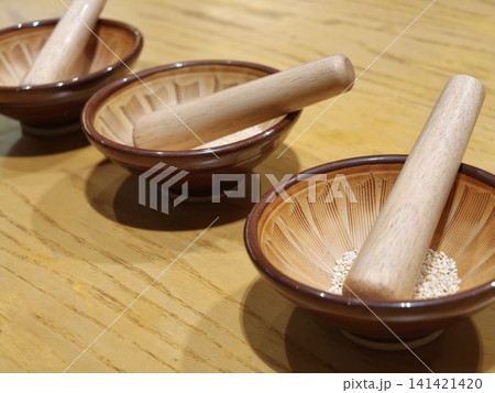 Three Wooden Mortars with Pestles and Sesame Seeds Closeup Three Wooden Mortars with Pestles and Sesame Seeds Closeup 141421420