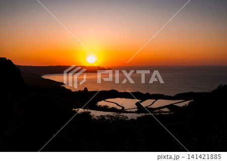 水平線に沈む黄金色の夕日と、夕焼けを美しく映し出す日本の美しい棚田の絶景 水平線に沈む黄金色の夕日と、夕焼けを美しく映し出す日本の美しい棚田の絶景 141421885