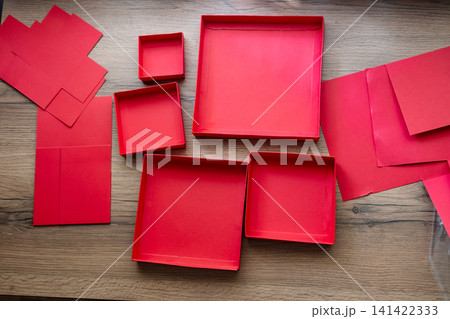 Lids from a red collapsible gift box gathered on a wooden table. Preparing a surprise. 141422333