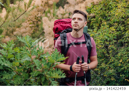 Portrait of handsome man trekking through forest path with backpack and poles Portrait of handsome man trekking through forest path with backpack and poles 141422459