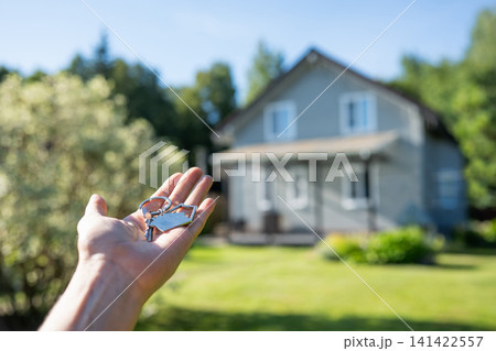 Hand holding house keys in front of blurred home 141422557