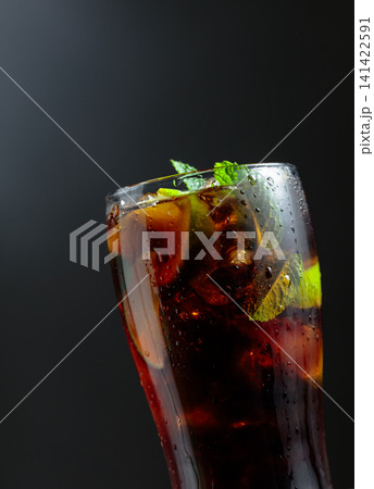 Cola with ice, lime slices, and mint in a fogged-up tall glass. 141422591