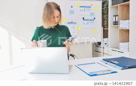 Happy female entrepreneur using smart phone in office. Happy female entrepreneur using smart phone in office. 141422907