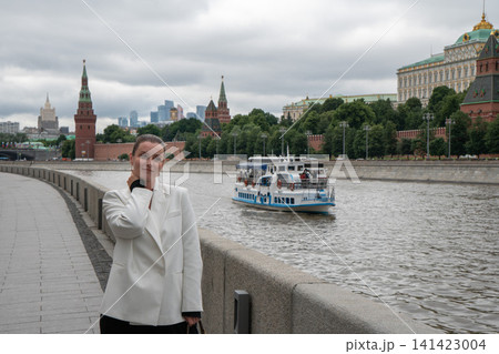Smiling woman points toward Kremlin while standing on Sofiyskaya Embankment in Moscow. Travel, sightseeing, urban lifestyle, famous landmark, architecture, tourism, city exploration Smiling woman points toward Kremlin while standing on Sofiyskaya Embankment in Moscow. Travel, sightseeing, urban lifestyle, famous landmark, architecture, tourism, city exploration 141423004