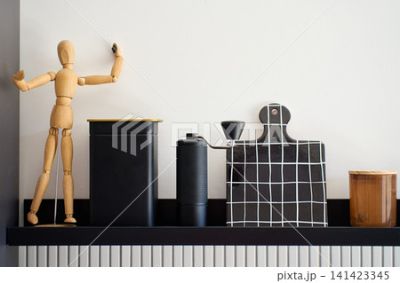 Manual coffee grinder stands on kitchen shelf with coffee accessories and storage container 141423345