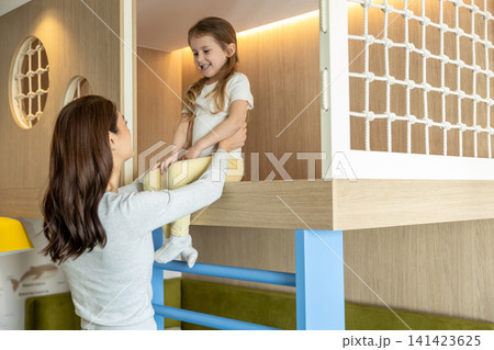 Mom and daughter playing together with dinosaurs and looking happy 141423625