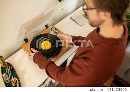 Young bearded caucasian man playing a stereo record Young bearded caucasian man playing a stereo record 141423966