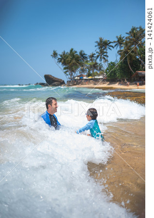 Caucasian father and son playing in ocean waves on tropical Sri Lankan beach Caucasian father and son playing in ocean waves on tropical Sri Lankan beach 141424061
