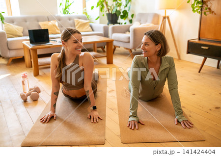 Happy female workout partners stretching in cobra pose 141424404