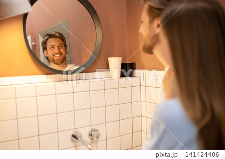 Waist up picture of a young couple looking in the mirror in the bathroom Waist up picture of a young couple looking in the mirror in the bathroom 141424406