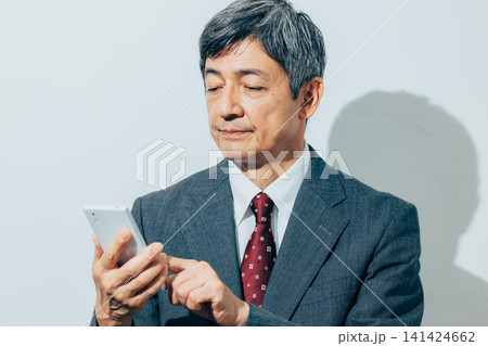 スマホで通話する中高年のビジネスマン スマホで通話する中高年のビジネスマン 141424662