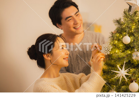 クリスマスツリーの飾りをつけるカップル クリスマスツリーの飾りをつけるカップル 141425229